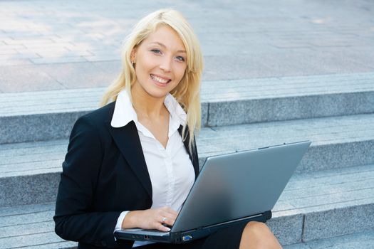 Young businesswoman sitting on stairway, using laptop computer