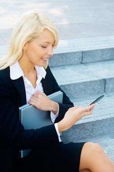 Young businesswoman sitting on stairway, looking at cell phone