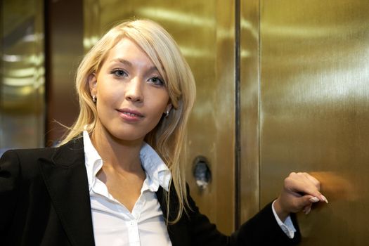 Young businesswoman leaning to metal door, looking at camera