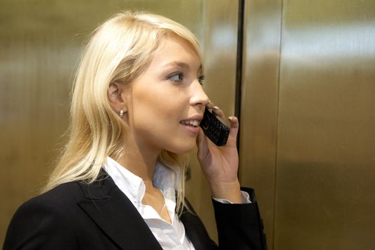 Young businesswoman using mobile phone by metal doors