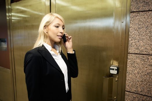 Young businesswoman using mobile phone outside heavy doors