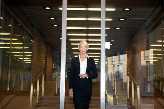 Businesswoman standing by building entrance, looking at camera