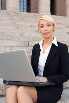 Businesswoman with laptop computer, looking at camera