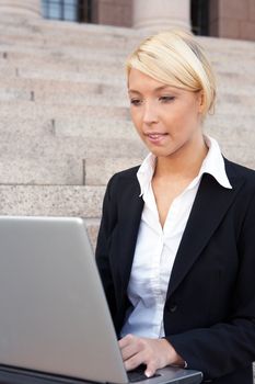 Businesswoman working with laptop computer outside building