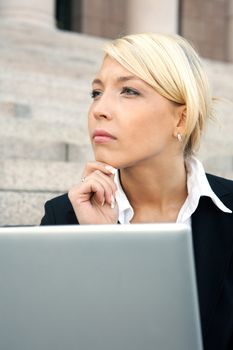 Businesswoman sitting with laptop computer, contemplating