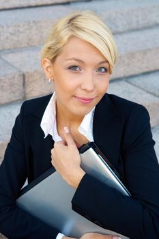 Businesswoman holding laptop computer, looking at camera