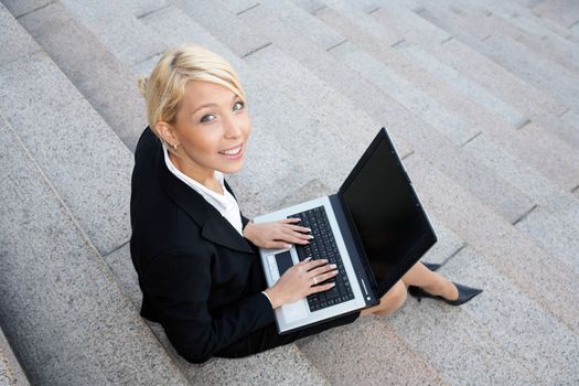 Businesswoman working with laptop computer, looking at camera