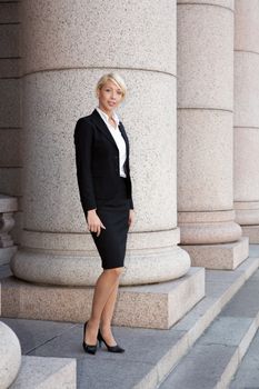 Young businesswoman standing by colonnade pillar