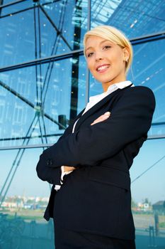 Young businesswoman standing by building arms crossed, smiling