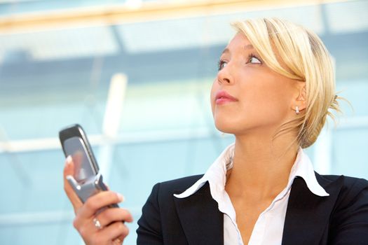 Businesswoman holding mobile phone, contemplating