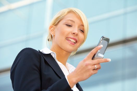 Businesswoman looking at mobile phone, smiling