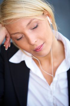 Young businesswoman wearing earphones with eyes closed