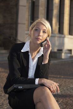 Young businesswoman usinh mobile phone in street outside building