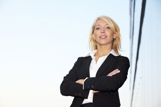 Young businesswoman standing arms crossed outside office building