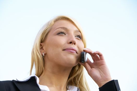 Young businesswoman smiling while using mobile phone outdoors