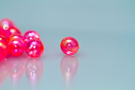 red beads on reflecting bluish surface in landscape orientation