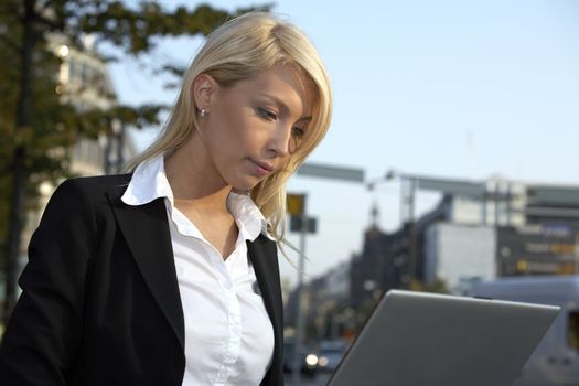 Young businesswoman working with laptop in street