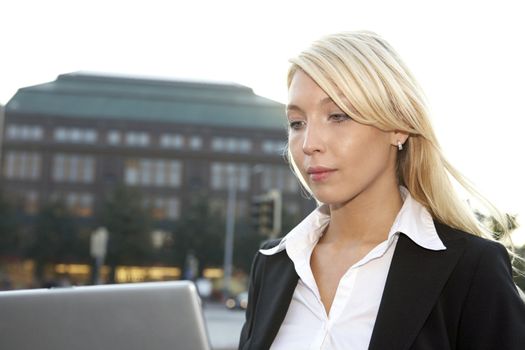 Close-up of young businesswoman working with laptop in city