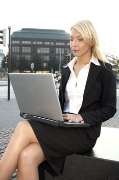 Close-up of young businesswoman using laptop in city