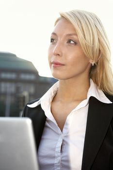 Young businesswoman contemplating with laptop in city