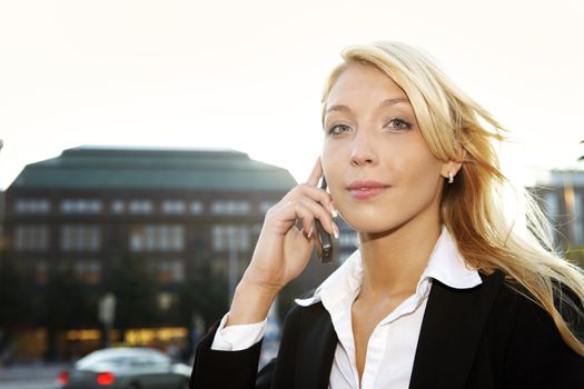 Young businesswoman looking at camera while using cell phone