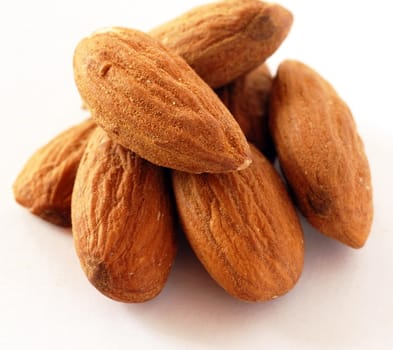 brown raw almonds over white background macro