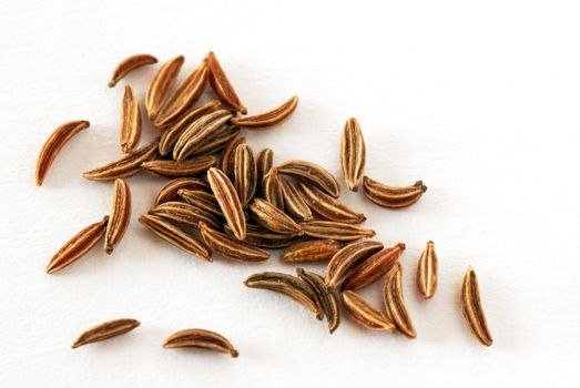 seeds of dry brown cumin over white background
