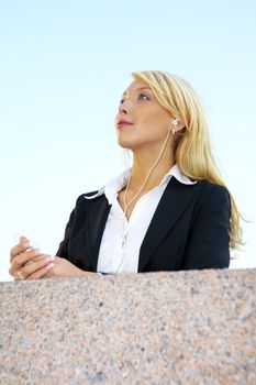 Young businesswoman listening to audio player wearing earphones