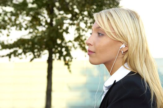 Profile of young businesswoman wearing earphones