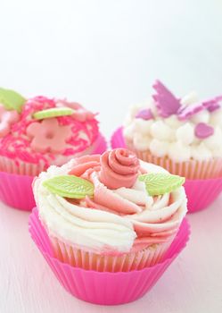 Vanilla cupcakes with buttercream icing and various decorations on white background