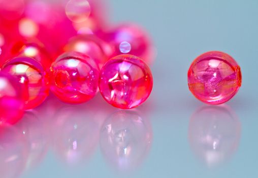 close up of red beads on reflecting bluish surface