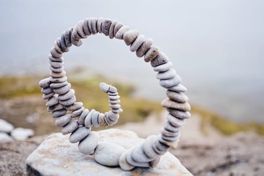 White spiral of pebbles on the boulder at the sea
