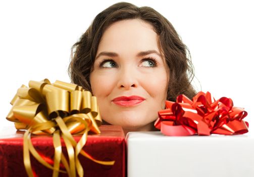 Beautiful young woman peeking over beautifully wrapped Christmas gifts and looking at copyspace
