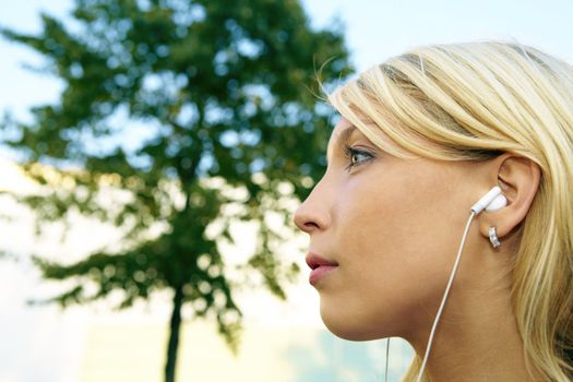 Low-angle profile of young businesswoman wearing earphones