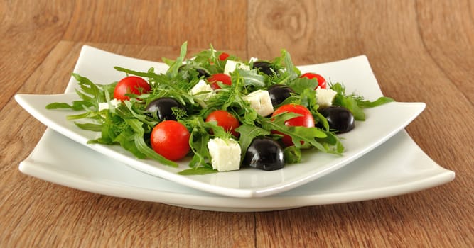 Salad of arugula with cherry tomatoes, slices of cheese and grapes