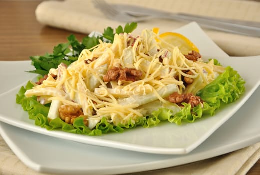 Salad with cheese and apple, walnuts and yogurt on lettuce leaves with lemon