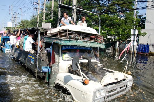 BANGKOK THAILAND – NOVEMBER 13: Truck carries a group of people to evacuate from the flooded area at Phahon Yothin Road during the massive flood crisis on November 13, 2011 in Bangkok, Thailand.