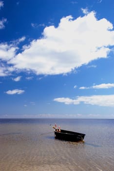 Plastic boat with floats tied at the seaside. Nice view of lake and sky.