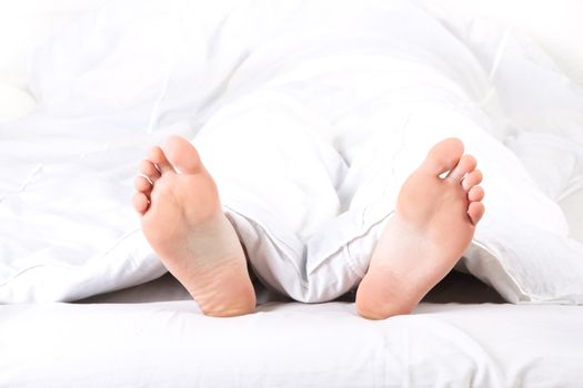 Men's feet under a white blanket