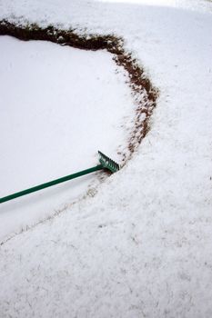 a green rake in a snow covered bunker on an irish golf course