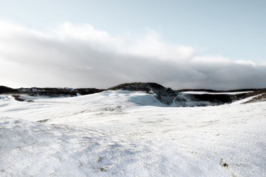 bunkers on a snow covered links golf course in ireland on a grey day in snowy winter weather