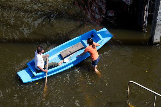 BANGKOK THAILAND – NOVEMBER 13: The old man rowing a boat to help flood victims female in area at Phahon Yothin Road during the massive flood crisis on November 13, 2011 in Bangkok, Thailand.