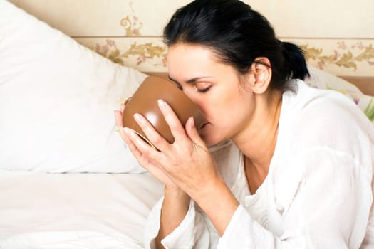 A young woman drinking coffee in the bed