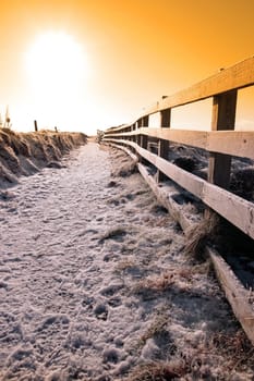 frosty winters view at ballybunion cliffside walk with bright sunset and fence