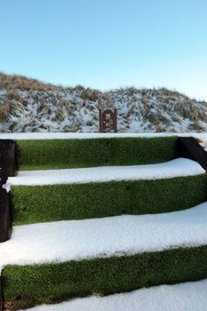 steps and sign on a tee thats on a snow covered links golf course in ireland