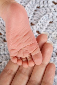 Foot of newborn baby resting on his mothers fingers