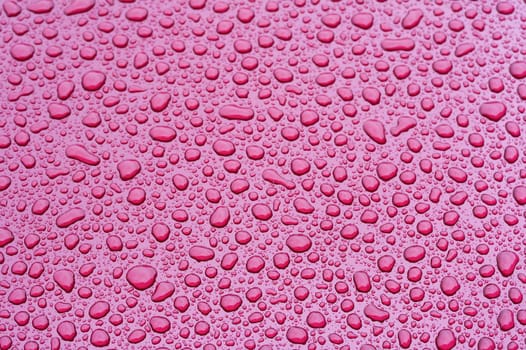 a picture of water drops on a red metal surface