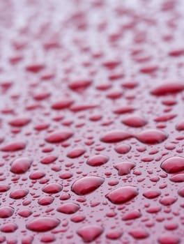 a picture of water drops on a red metal surface