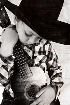 Beautiful blond cowboy wearing a hat holding guitar