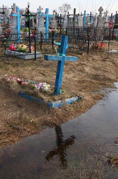 Flooded rural cemetery graves and display the cross in the water